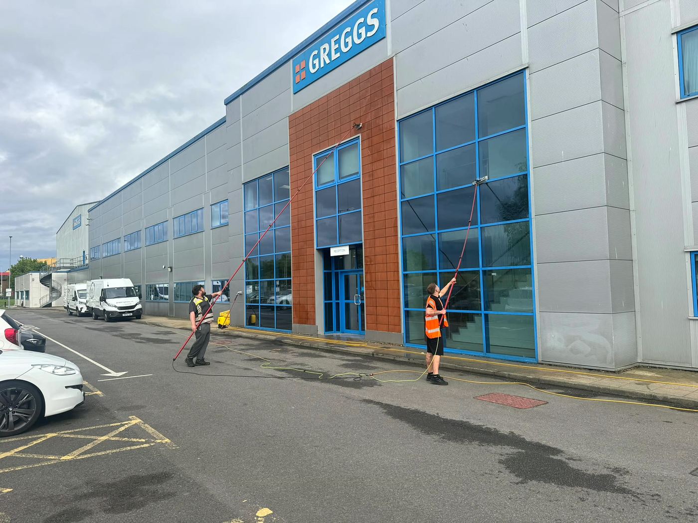 Two PropertyKleen cleaners using water-fed poles at Greggs