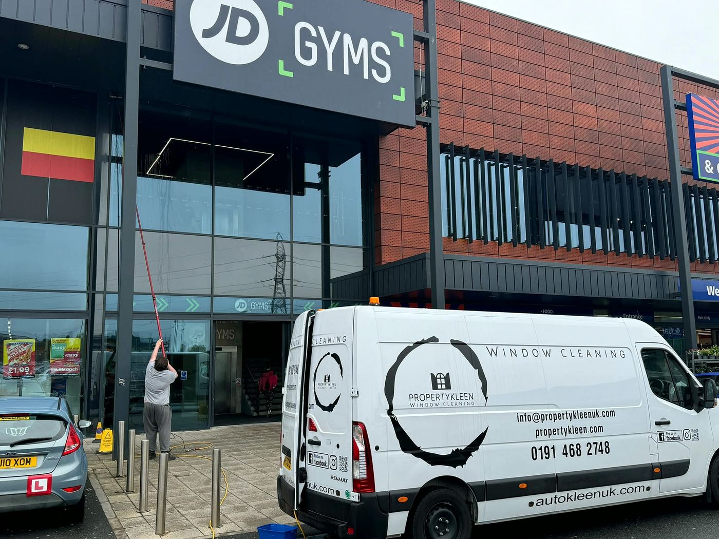 PropertyKleen van and team cleaning windows at JD Gyms