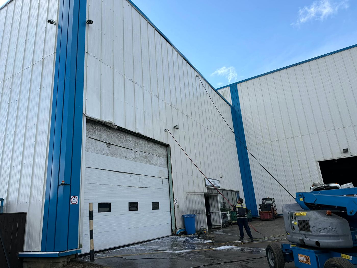 Water-fed poles cleaning tall warehouse cladding