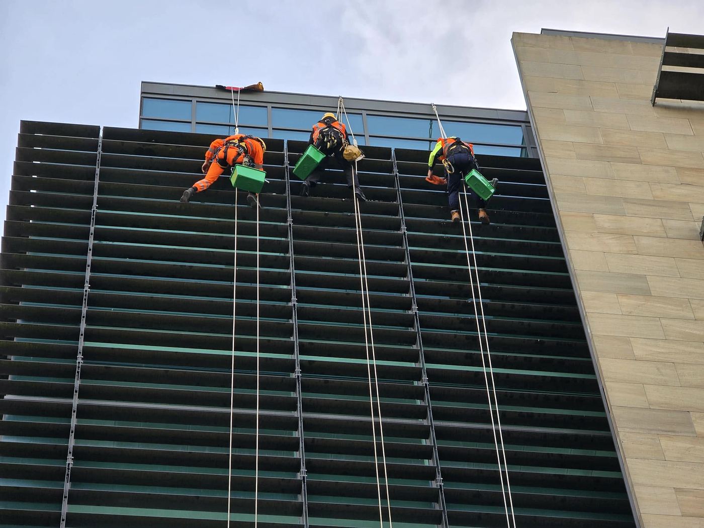 Three rope access technicians cleaning a high-rise office façade
