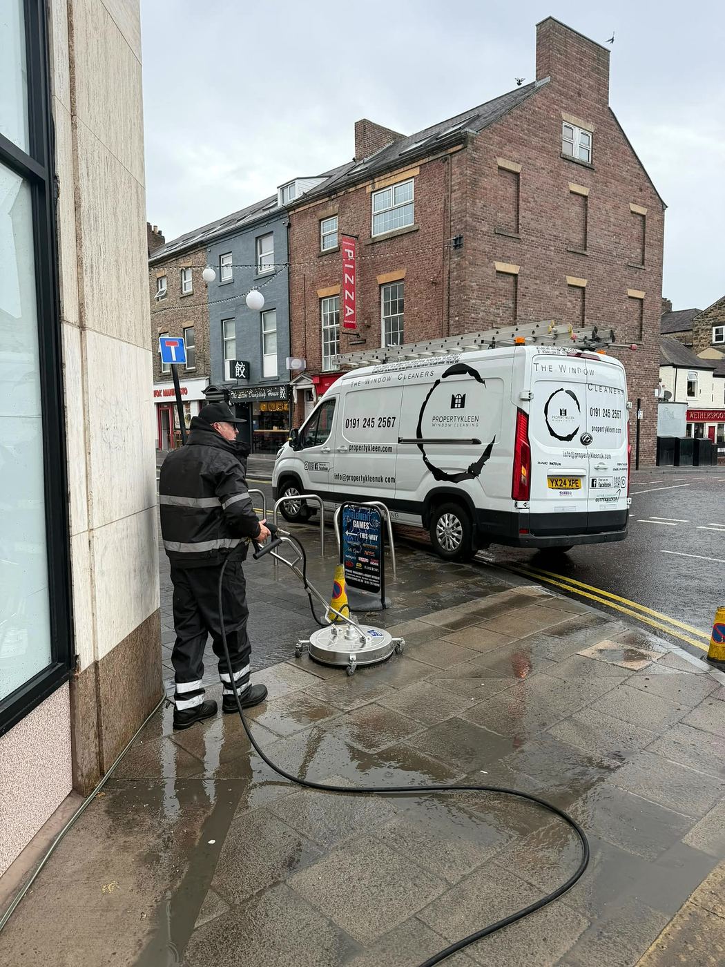 Rotary surface cleaner on a shopfront pavement with the PropertyKleen van behind